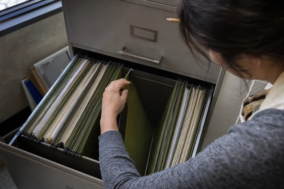 An empty hanging folder held open inside a filing drawer, nothing inside, close detail
